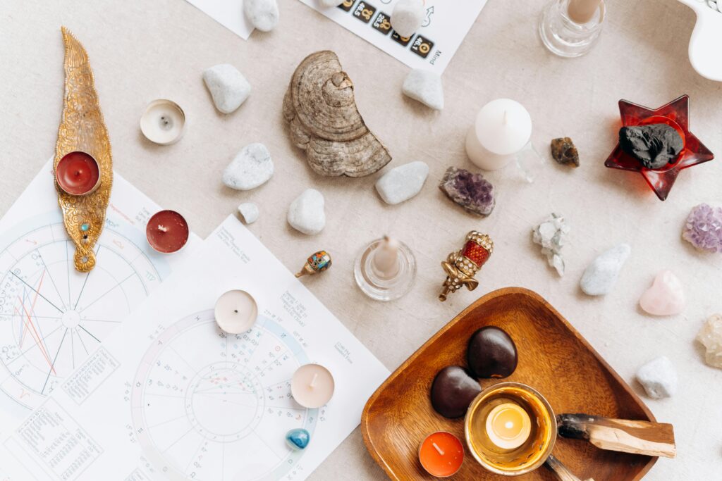 A spiritual altar setup with healing crystals, candles, astrology charts, and ritual tools arranged for meditation and energy work.