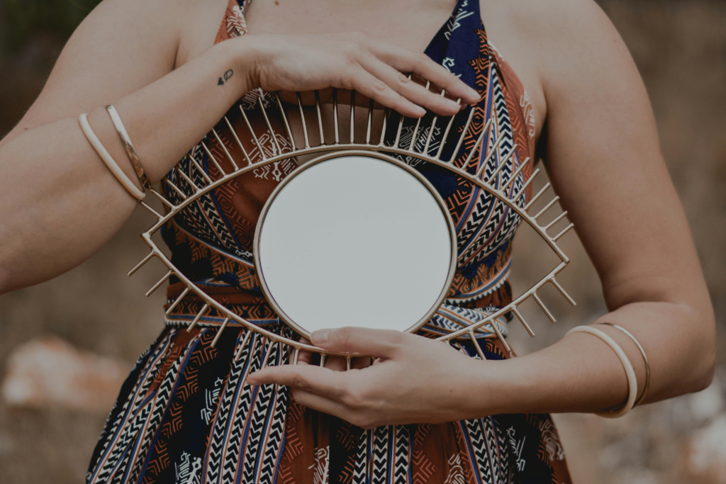 A person holding a circular mirror framed like an eye, symbolising self-reflection, awareness, and inner observation.