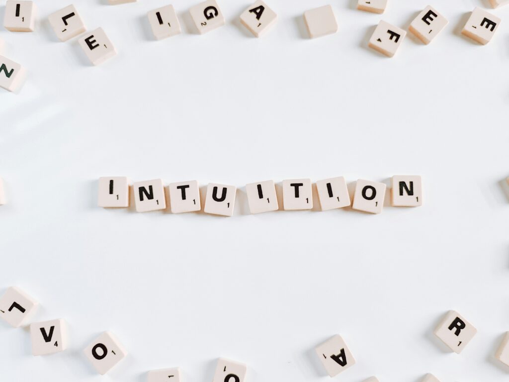 The word βintuitionβ spelled out with letter tiles, symbolising intuition vs ego and the choice to trust inner guidance over mental noise.