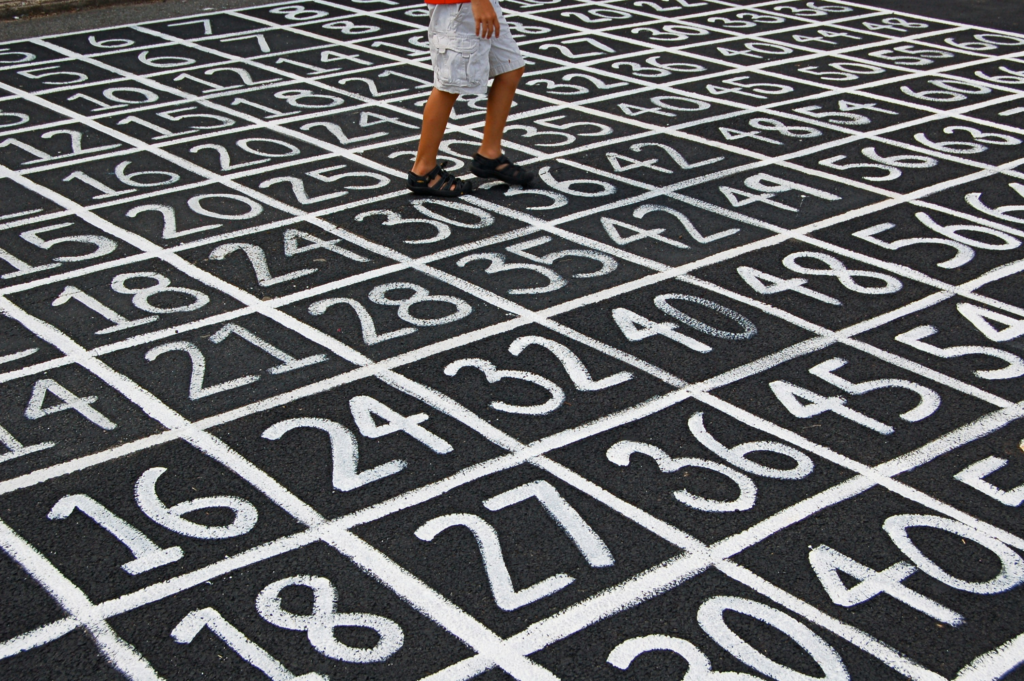A person walking across a large grid of painted numbers on the ground, symbolizing number patterns and numerical exploration.