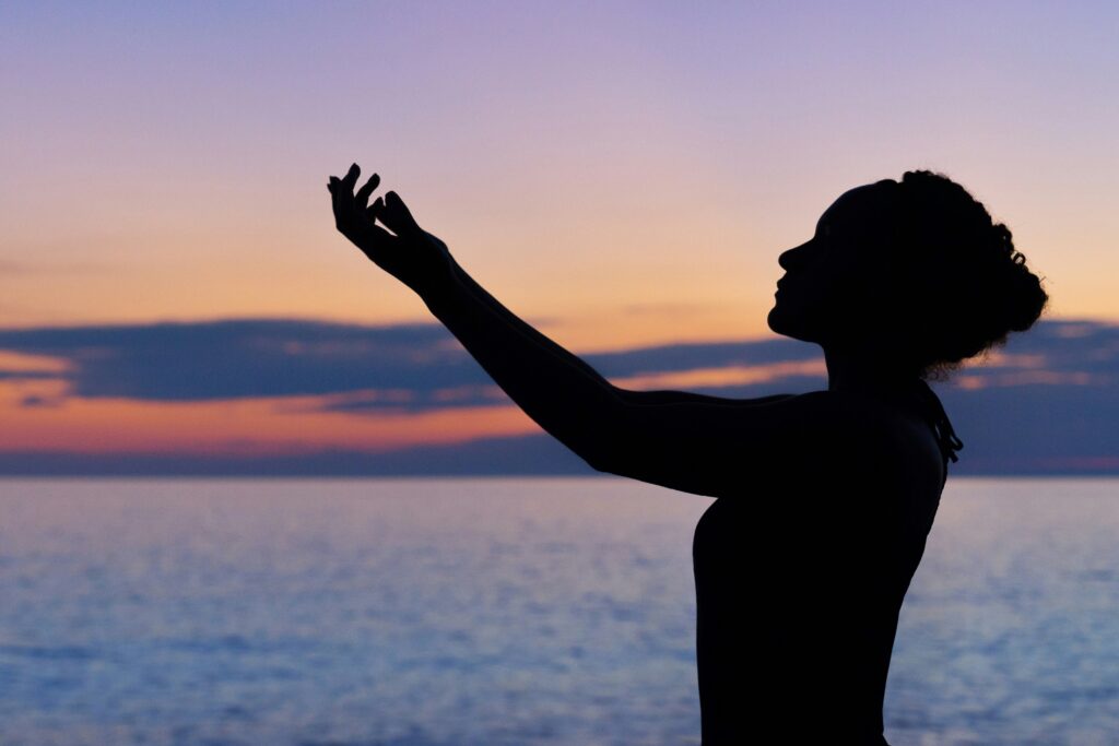 Silhouette of a person embracing stillness and presence during a mindfulness practice at sunset