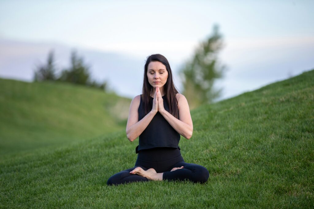 Woman sitting in a peaceful outdoor setting, practicing mindfulness and breath awareness, illustrating meditation benefits and practices for mental clarity and inner balance.