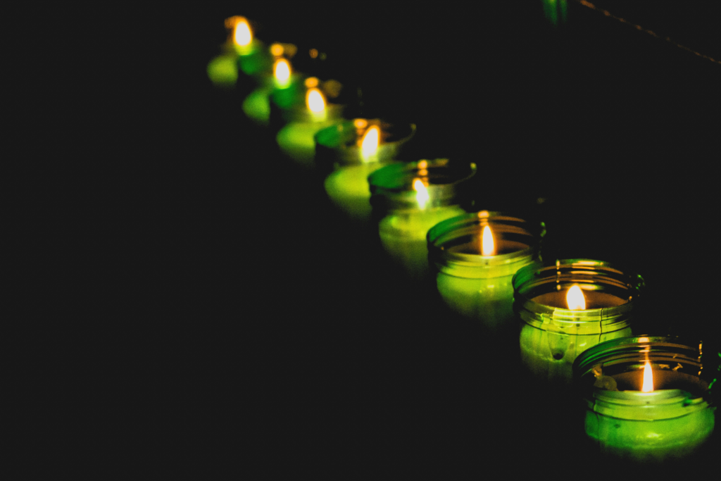 Row of softly glowing candles in glass holders creating a peaceful and contemplative atmosphere.