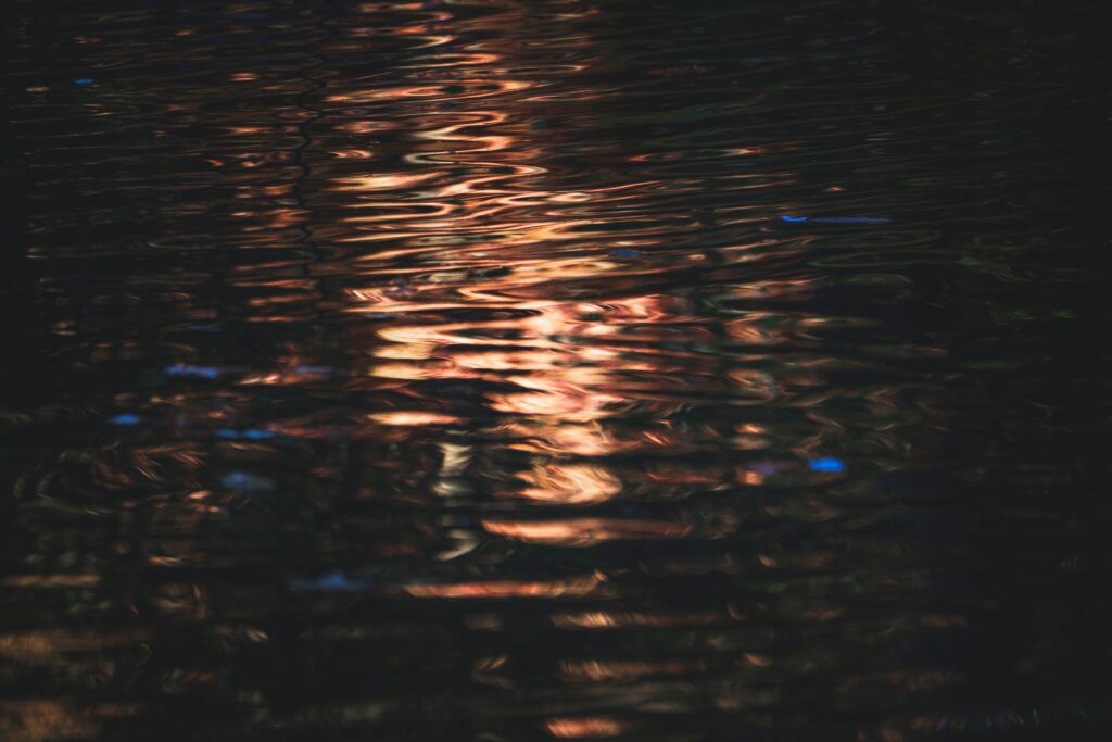 Soft reflections of light moving through dark water, representing observing the darkness without judgment as thoughts and emotions gently pass through awareness.