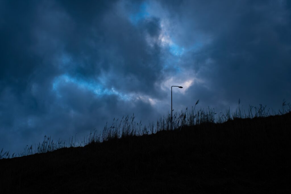 Dark storm clouds gathering above a quiet hillside at dusk, reflecting the stillness and uncertainty that often accompany inner emotional conflict.